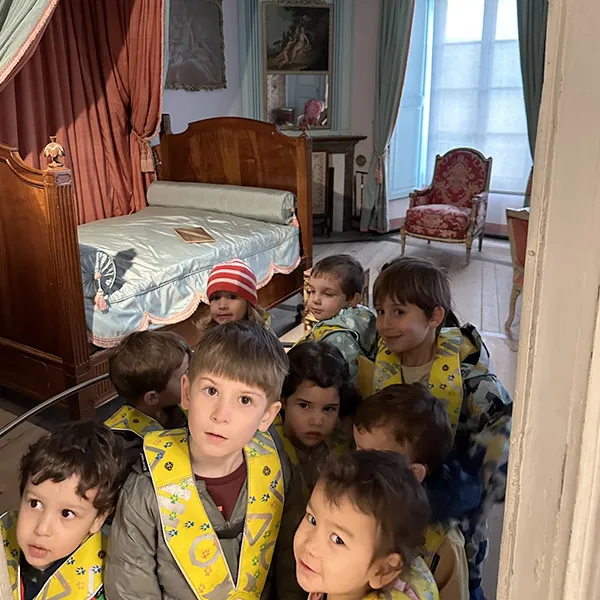 Petits groupes d’enfants explorant une salle historique avec des jeux éducatifs.