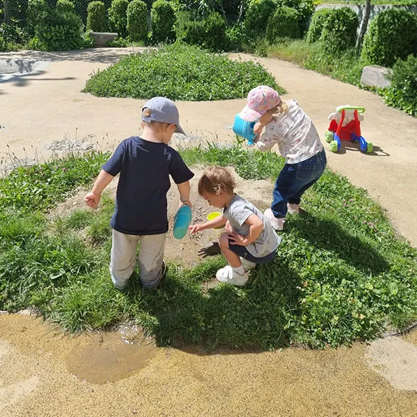 Un enfant éclabousse joyeusement dans un bac d’eau à la crèche Le Microcosme à Lausanne.