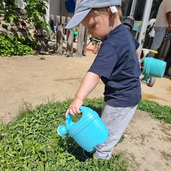 Un enfant éclabousse joyeusement dans un bac d’eau à la crèche Le Microcosme à Lausanne.