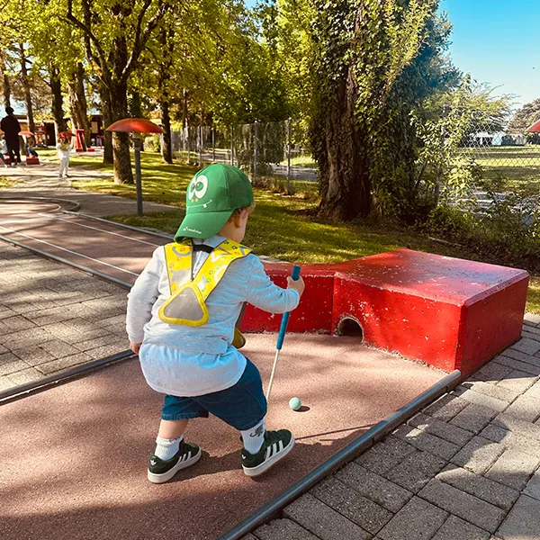Enfant de la crèche Le Microcosme à Lausanne jouant au mini-golf lors d’une activité de motricité ludique.